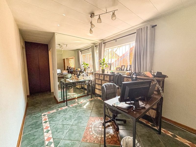 A bedroom featuring tiled flooring, built-in cupboards, and security bars on the windows, offering a functional space with potential for modernization.