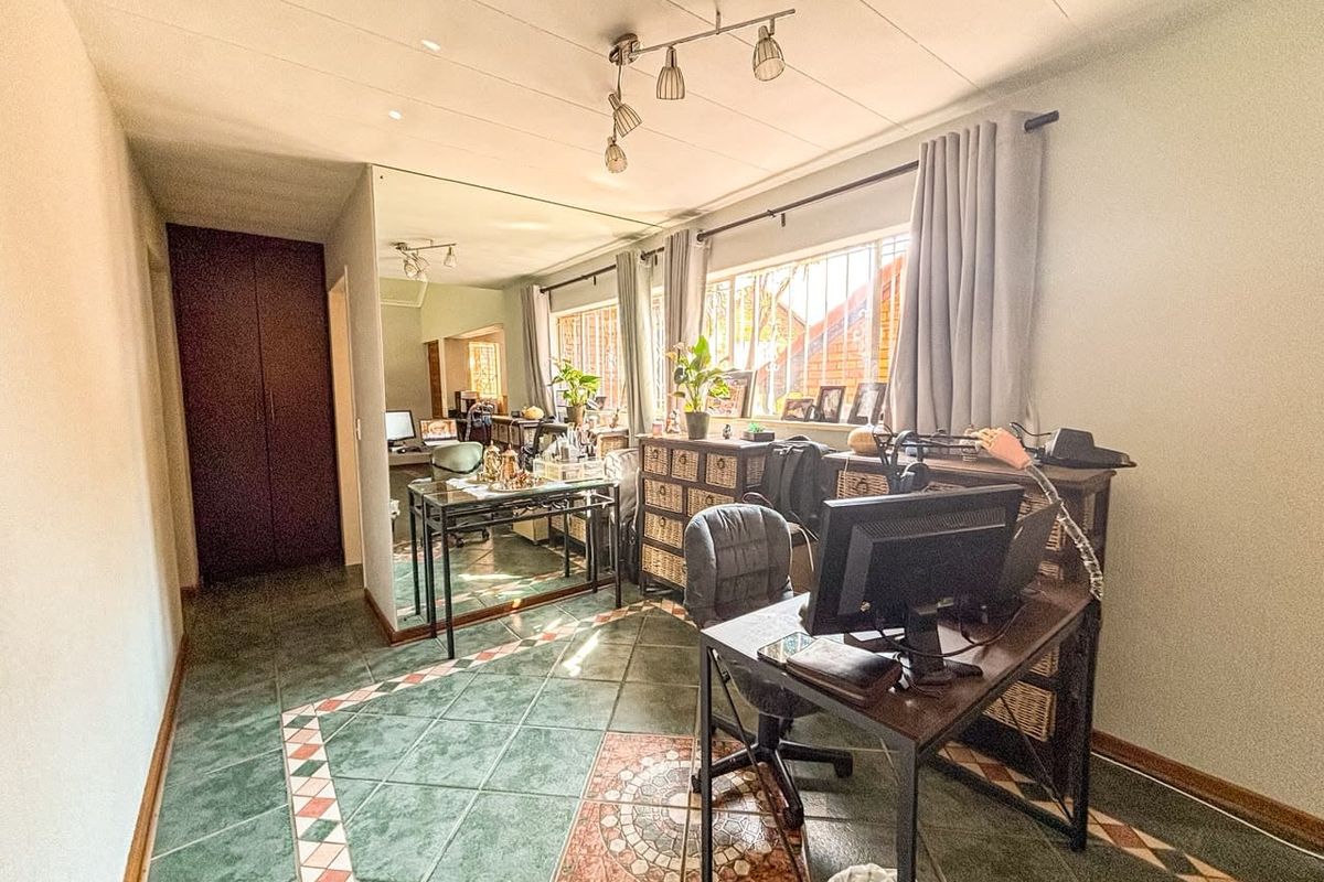 A bedroom featuring tiled flooring, built-in cupboards, and security bars on the windows, offering a functional space with potential for modernization.