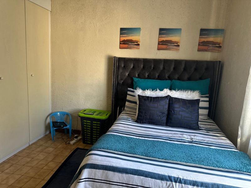 A functional bedroom featuring tiled flooring and a built-in wardrobe with textured wall finishes.