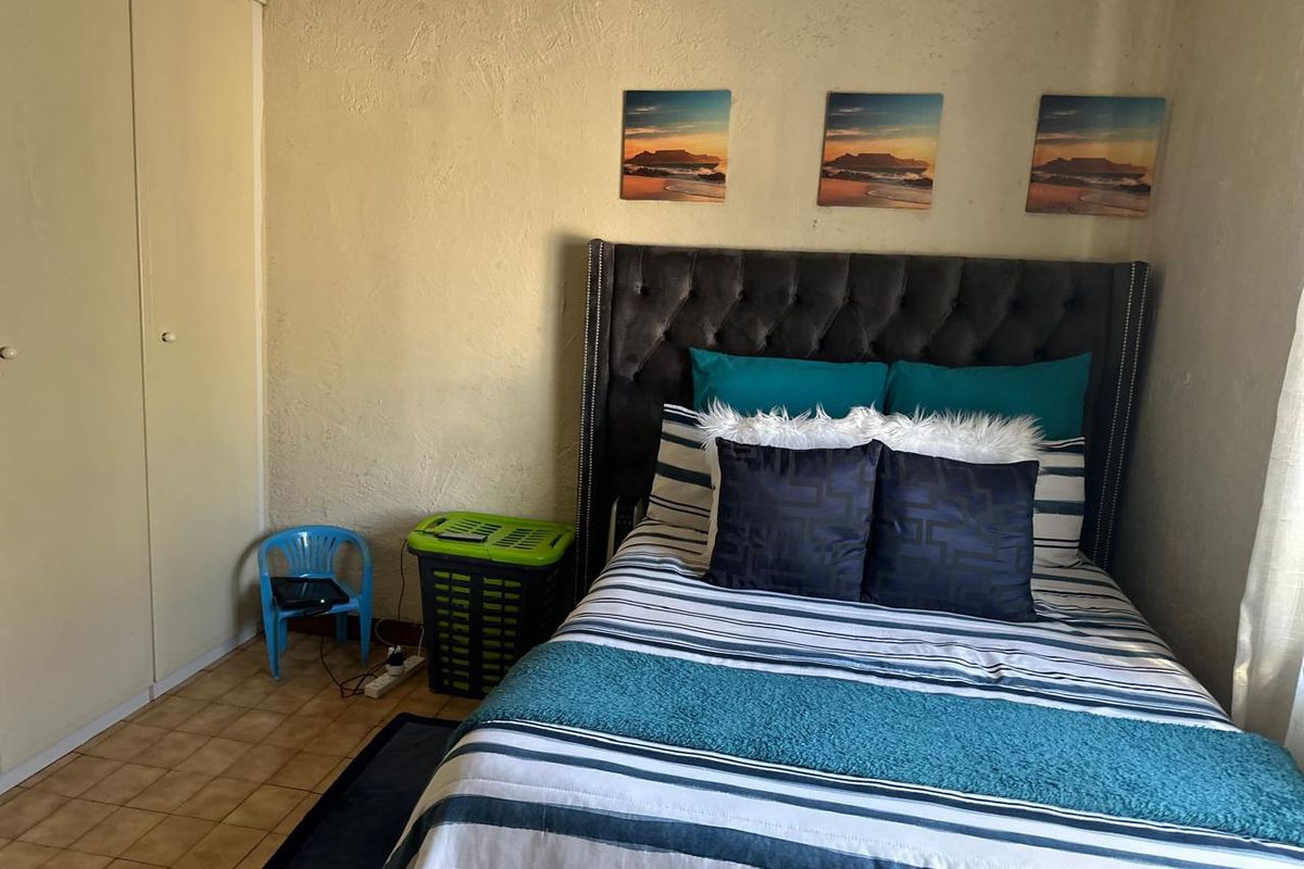 A functional bedroom featuring tiled flooring and a built-in wardrobe with textured wall finishes.
