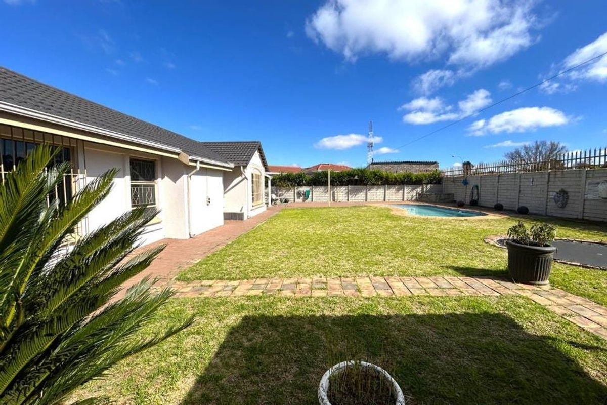 Spacious rear garden featuring a swimming pool, paved patio area, and secure perimeter walling, offering a private outdoor space.
