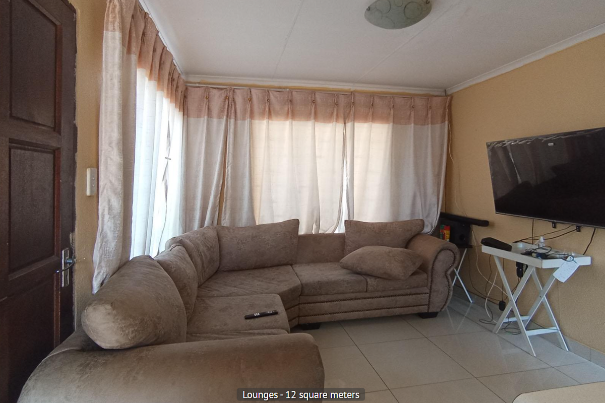 A compact living room featuring tiled flooring and a large window with curtains.
