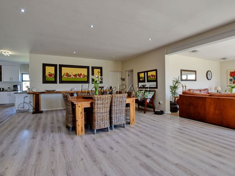Spacious open-plan living and dining area featuring modern laminate flooring, recessed lighting, and a seamless transition to a functional kitchen space.