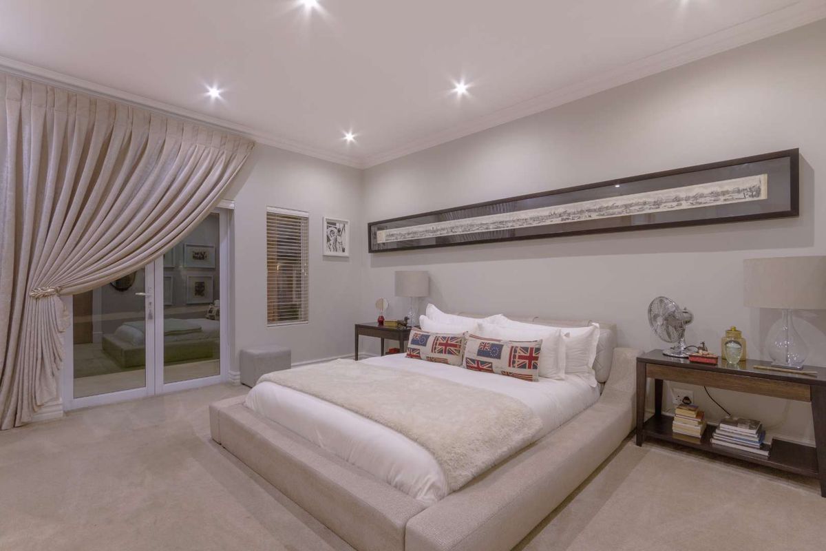 A spacious, well-lit bedroom featuring neutral carpeting, recessed downlighting, and a sliding glass door providing access to the exterior.
