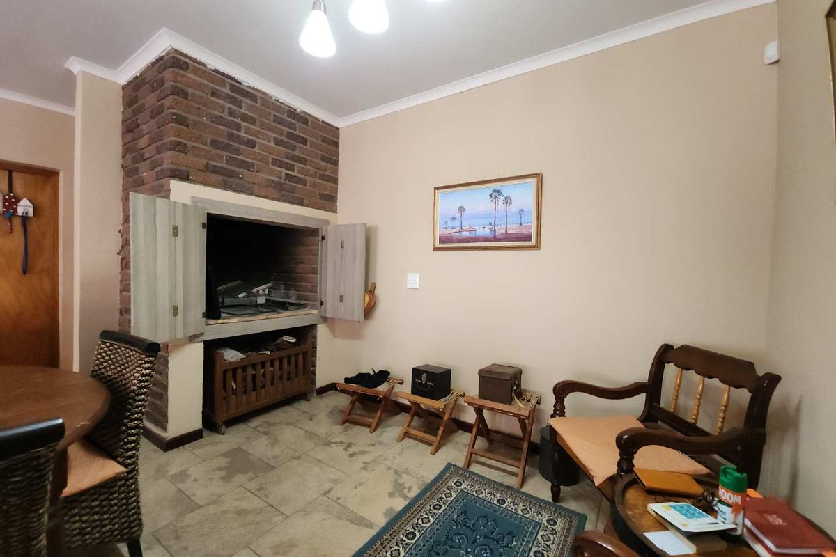 A living area featuring a built-in brick fireplace with cabinet doors and tiled flooring.