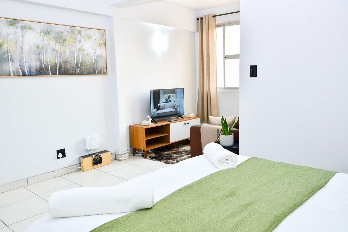 A bright bedroom featuring tiled flooring and a window, providing a clean and functional living space.