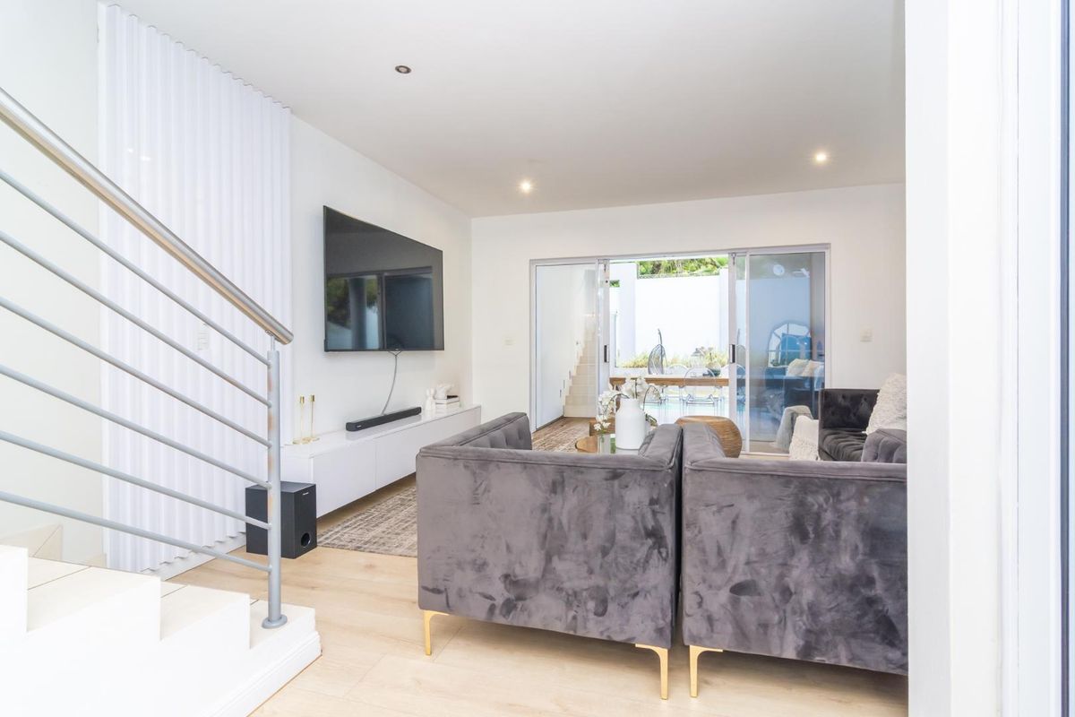 Bright and modern living area featuring light wood-look flooring, recessed lighting, and sliding glass doors that open to an outdoor patio space.