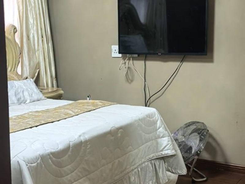 A bedroom featuring laminate flooring and crown molding, currently showing signs of wear on the walls and exposed wiring.