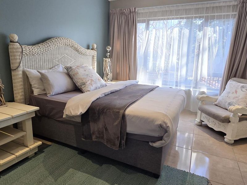 A bedroom featuring tiled flooring and large windows with curtain tracks, providing natural light and a view of the exterior.