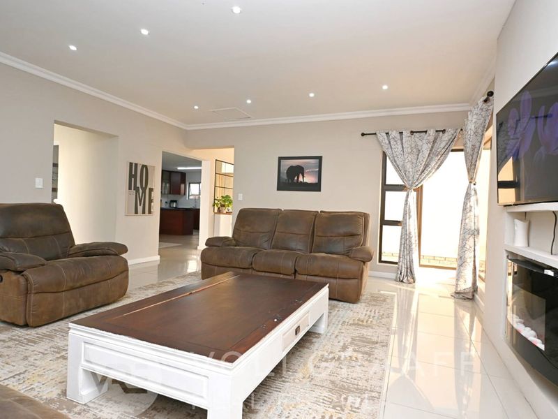 Spacious living room featuring polished tiled floors, recessed downlighting, and a modern built-in fireplace, creating a comfortable and well-maintained atmosphere.