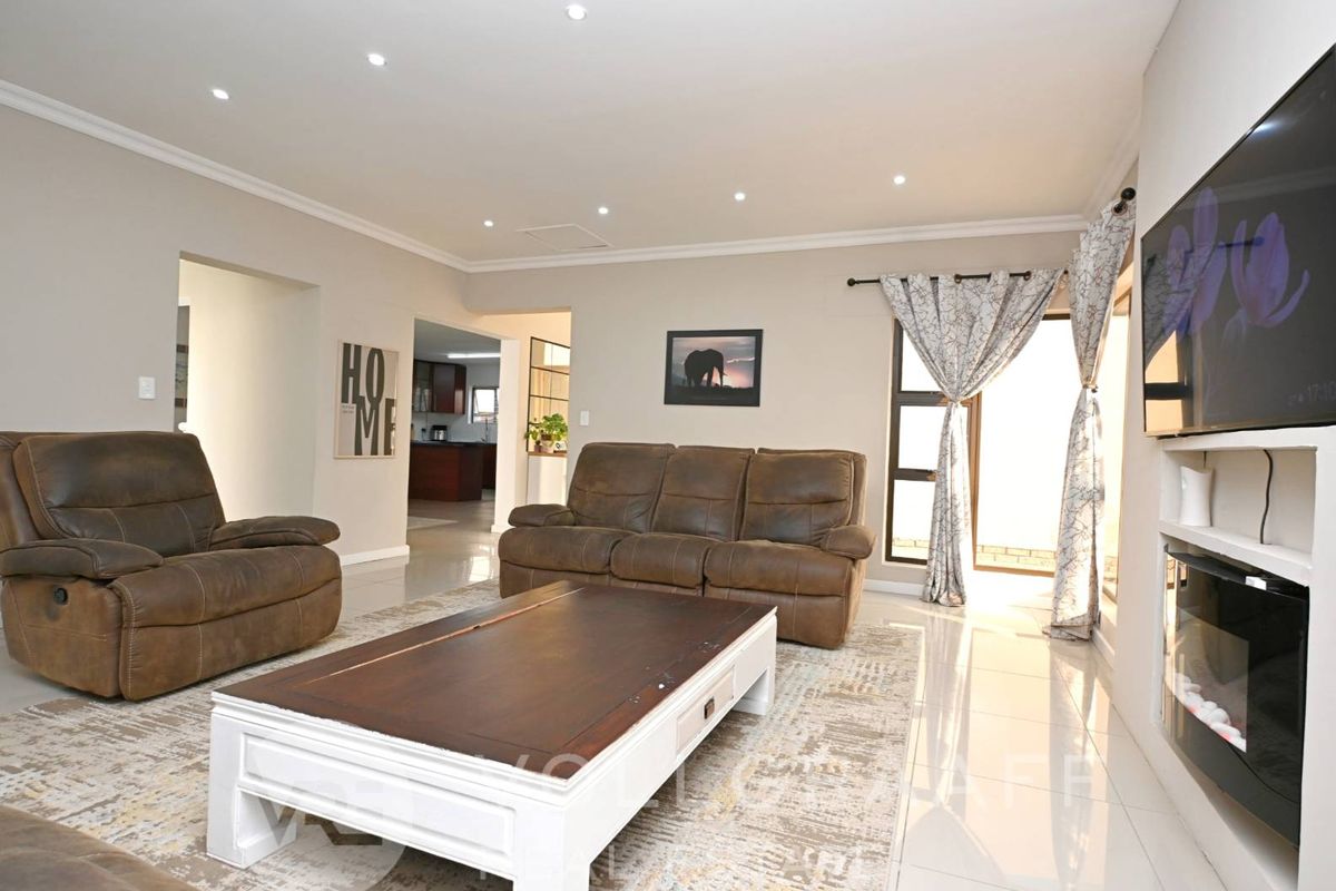 Spacious living room featuring polished tiled floors, recessed downlighting, and a modern built-in fireplace, creating a comfortable and well-maintained atmosphere.