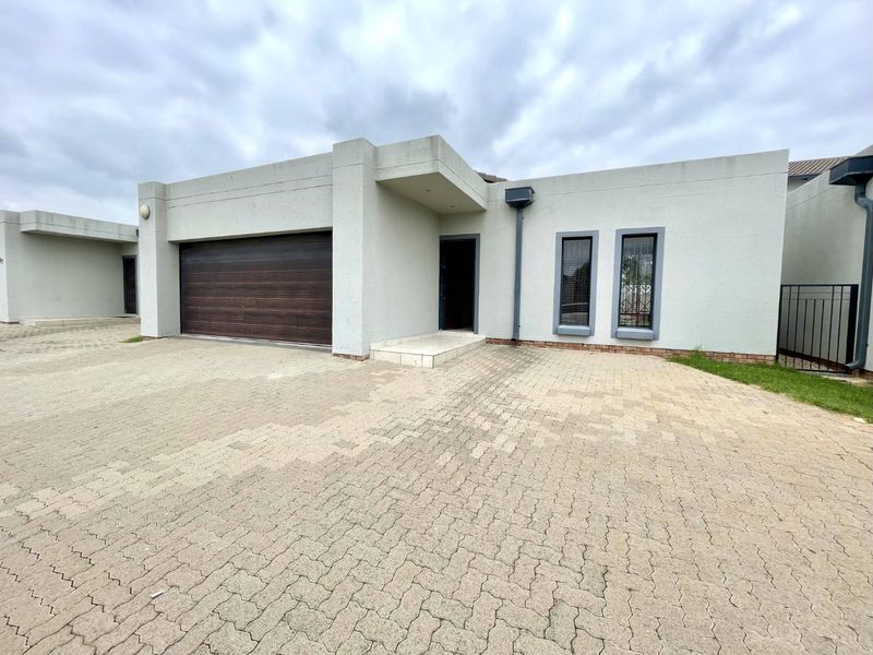 Front elevation of a modern townhouse featuring a paved driveway, double garage, and secure entrance.