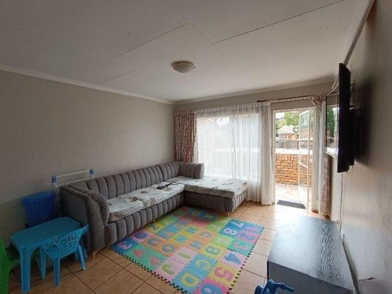 A living room featuring tiled flooring and a sliding glass door providing access to an outdoor patio area.