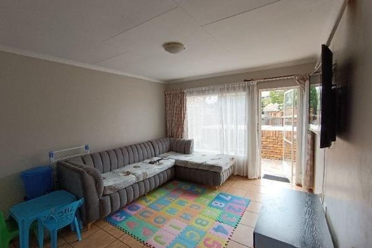 A living room featuring tiled flooring and a sliding glass door providing access to an outdoor patio area.