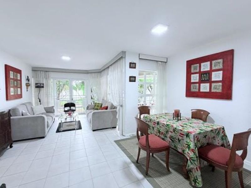Spacious open-plan living and dining area featuring neutral tiled flooring, ample natural light through large windows, and direct access to the outdoor patio.