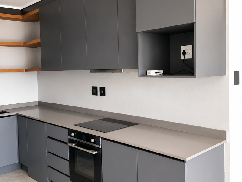 Modern kitchen featuring sleek grey cabinetry, stone countertops, built-in oven, electric hob, and open wooden shelving with neutral tiled flooring.