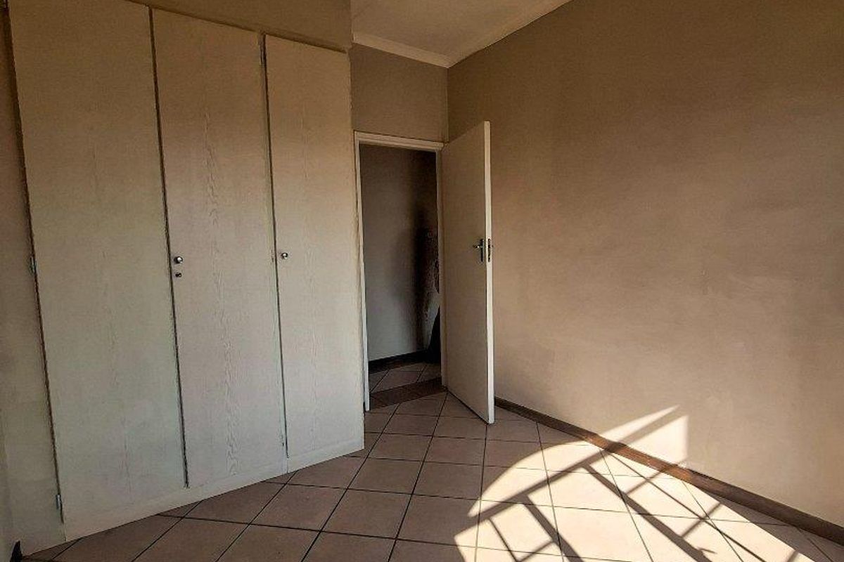 A vacant bedroom featuring built-in cupboards, tiled flooring, and a standard ceiling light fixture.