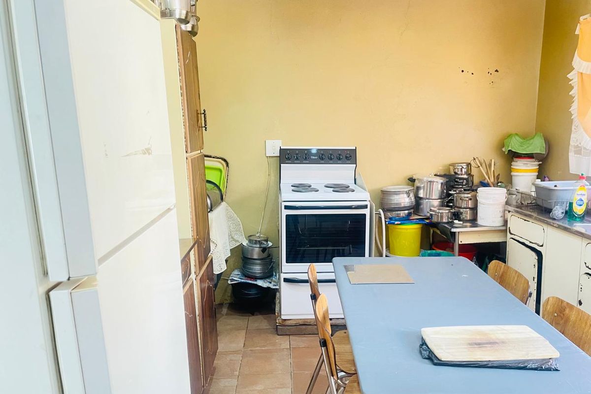 A functional kitchen space featuring a freestanding stove, basic cabinetry, and tiled flooring, offering potential for modernization and cosmetic updates.
