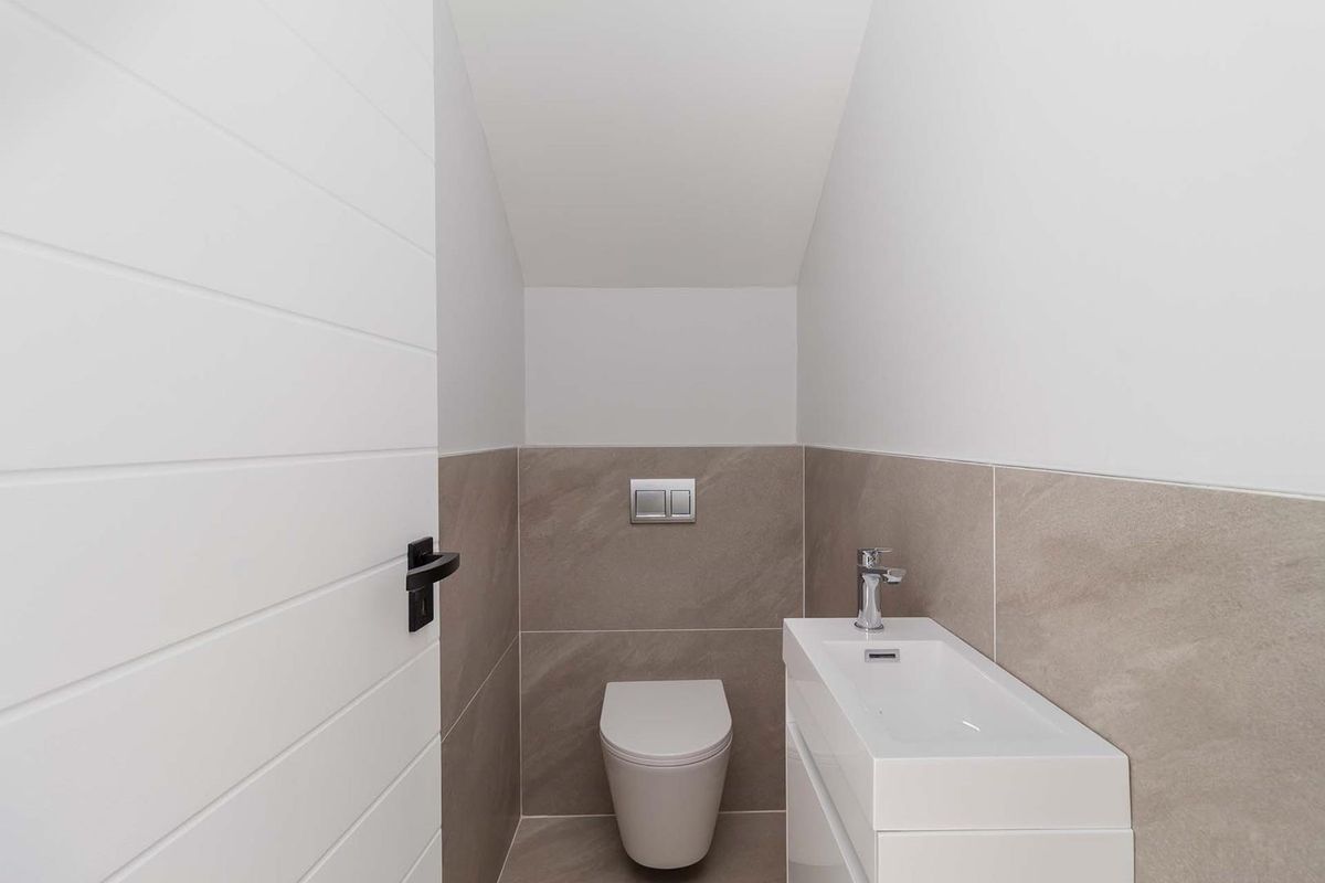 A modern, compact guest bathroom featuring a wall-hung toilet with a concealed cistern and a sleek vanity basin with a mixer tap.