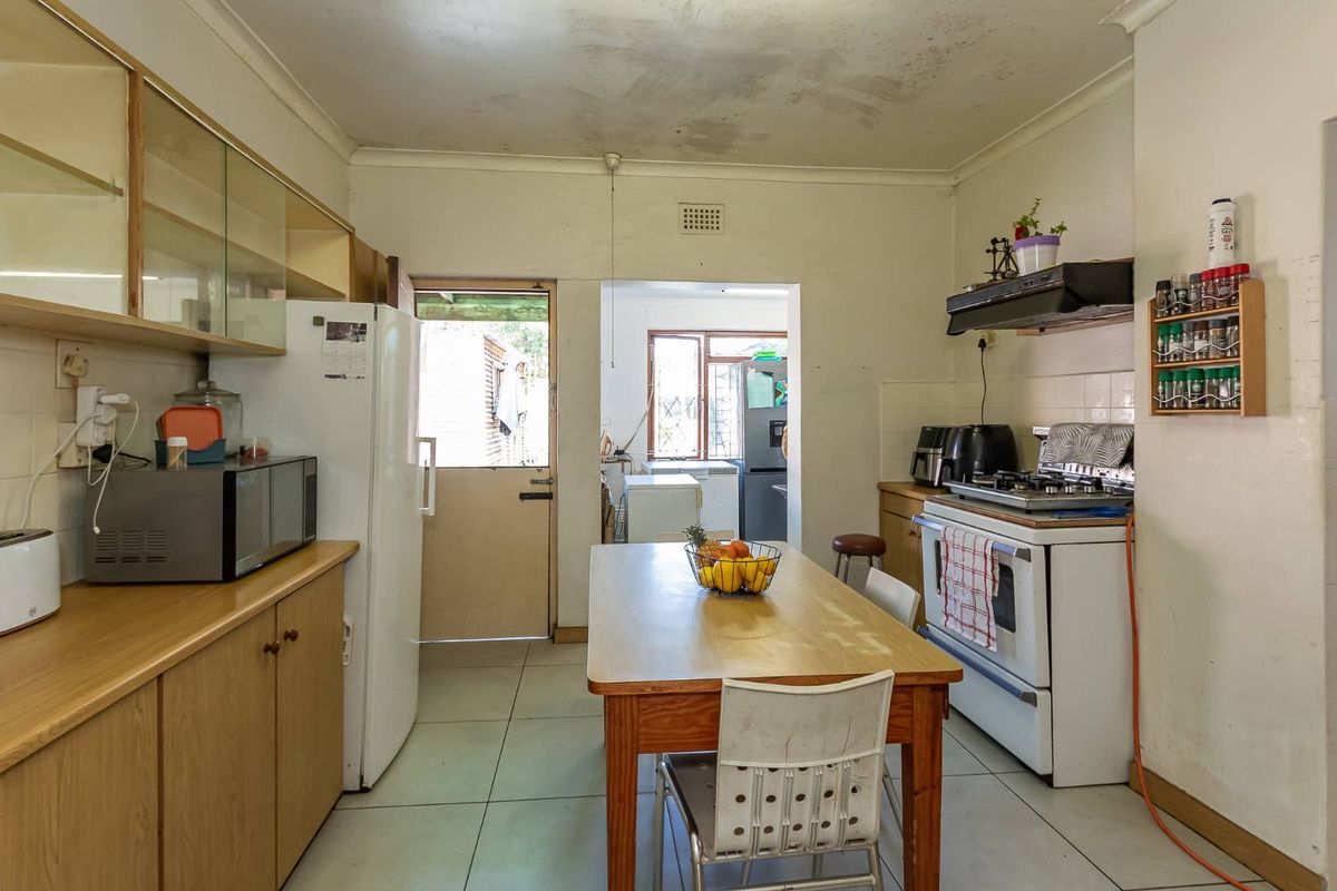 A functional kitchen featuring tiled flooring, built-in cabinetry, and a gas stove, with potential for cosmetic updates to modernize the space.
