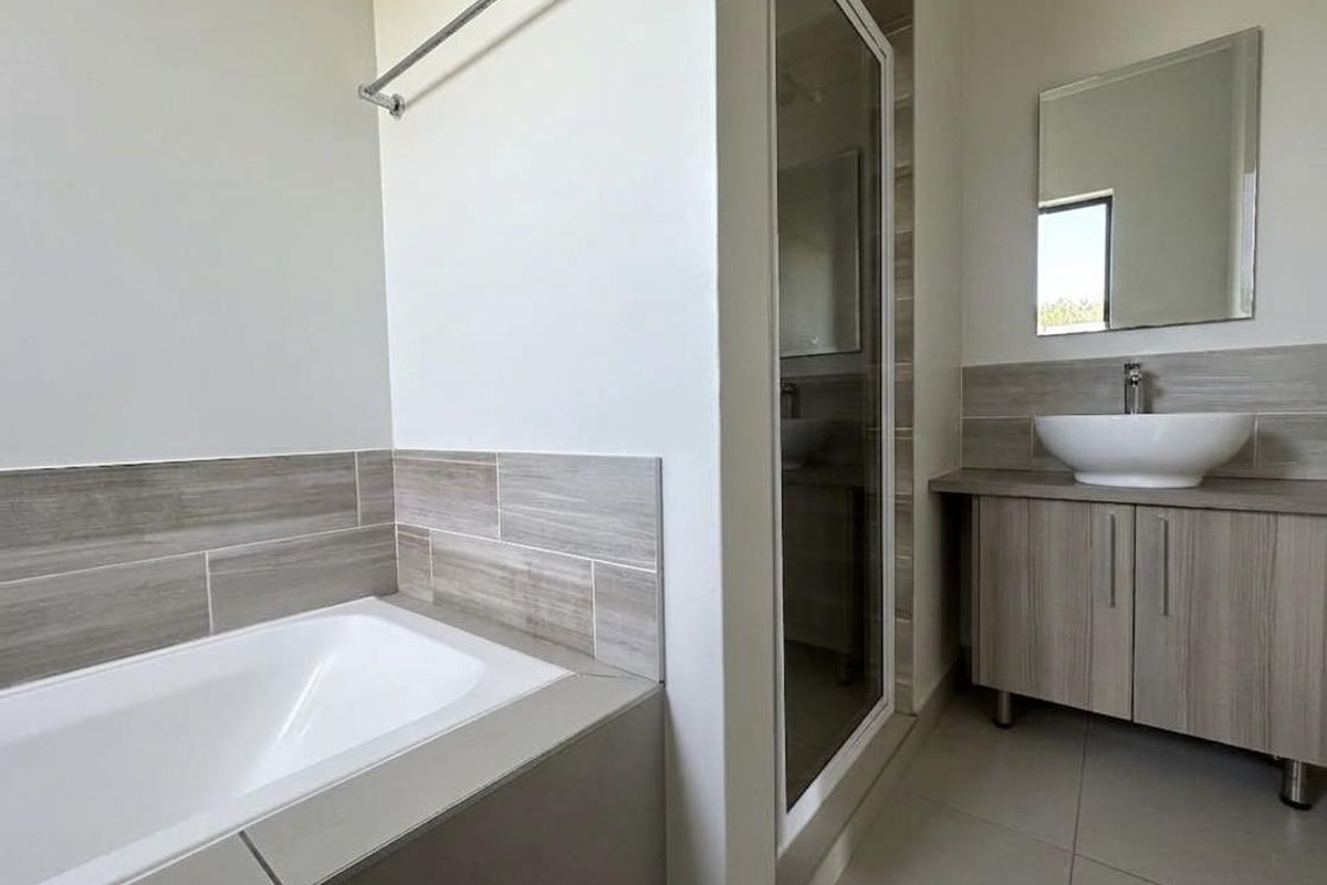 Modern bathroom featuring a built-in bathtub, separate glass-enclosed shower, and a vanity unit with a vessel sink and wall-mounted mirror.