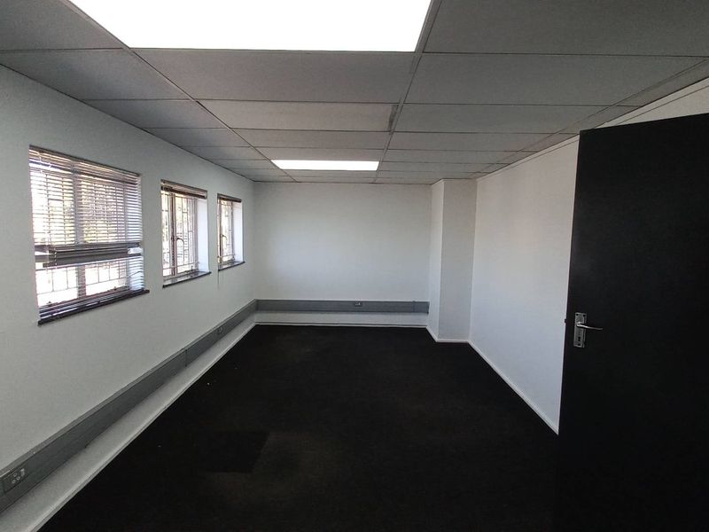 A vacant office space featuring a suspended ceiling, carpeted flooring, and multiple windows with fitted blinds, suitable for a professional workspace.