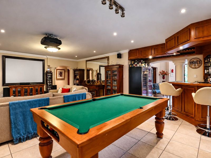 Spacious entertainment room featuring a built-in bar, tiled flooring, recessed lighting, and a dedicated home cinema setup with a projector and screen.