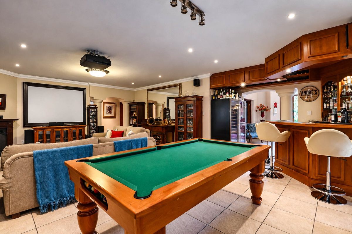 Spacious entertainment room featuring a built-in bar, tiled flooring, recessed lighting, and a dedicated home cinema setup with a projector and screen.