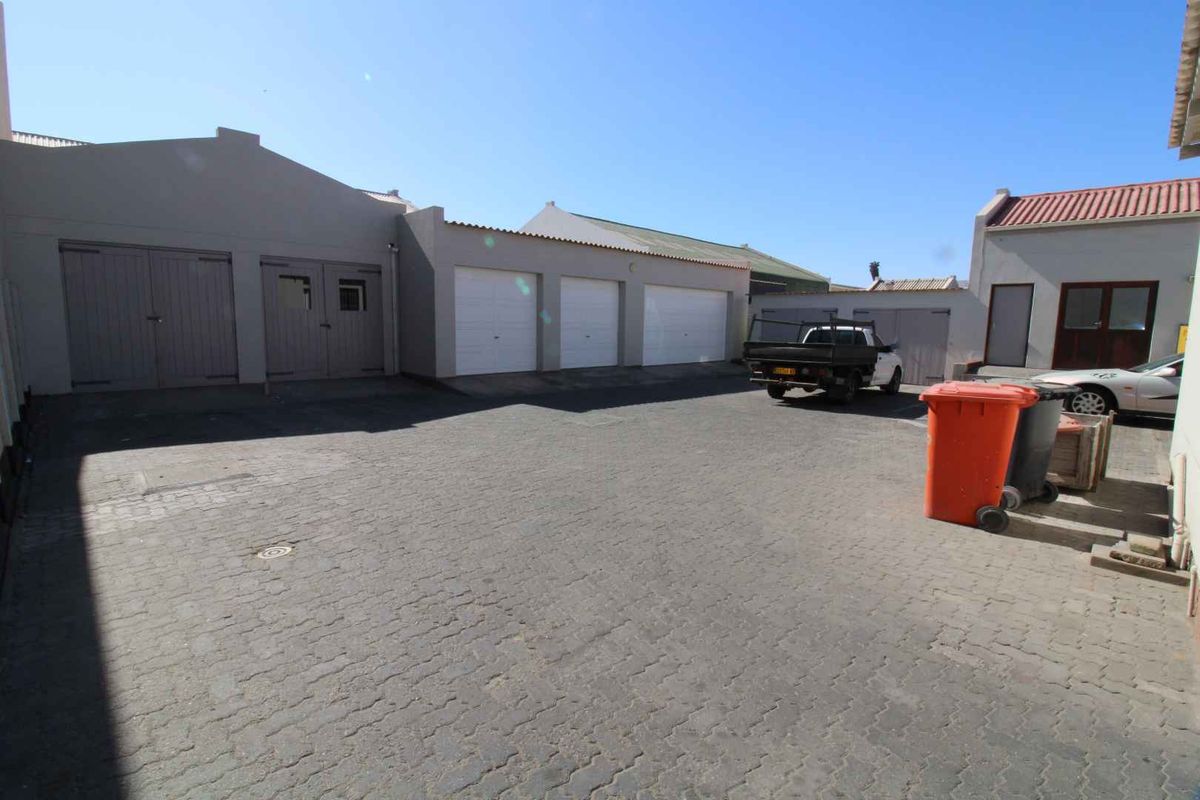 A paved courtyard area featuring multiple garage doors and access points, providing functional parking and utility space for the property.