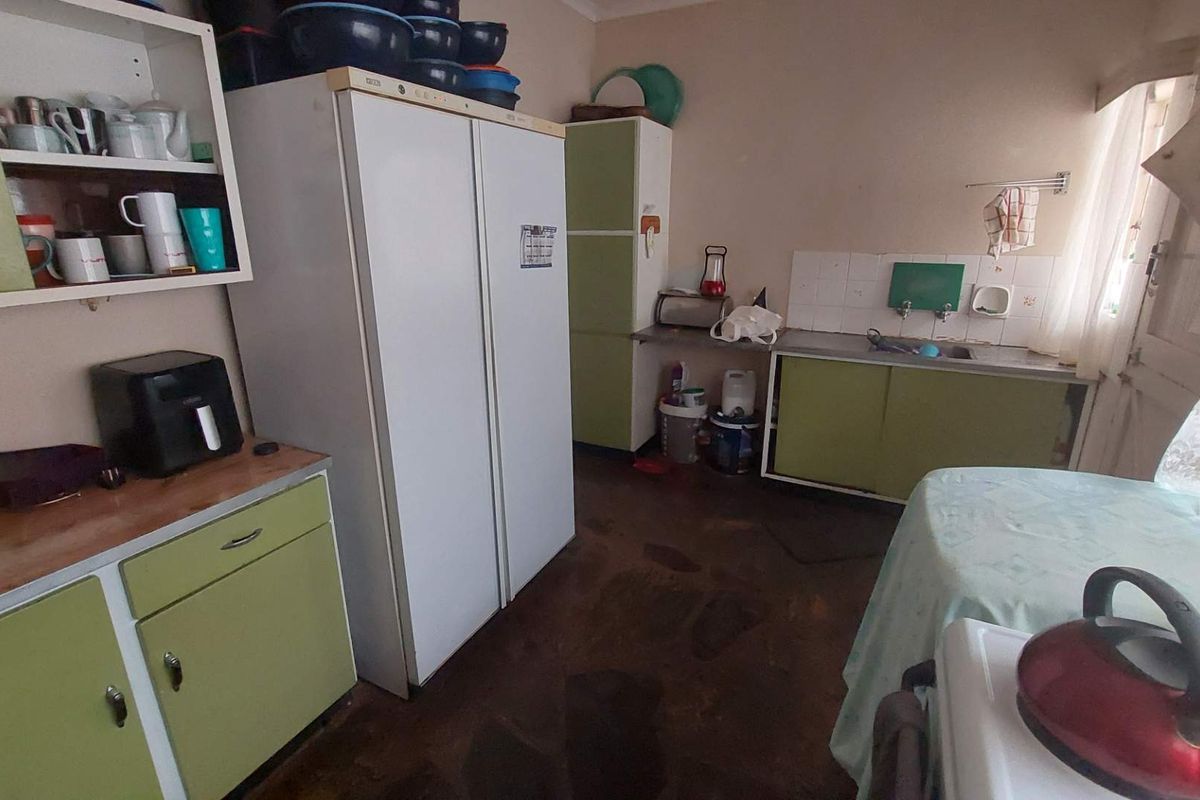 A dated kitchen featuring retro green cabinetry, laminate countertops, and a stainless steel sink, offering potential for a modern renovation.