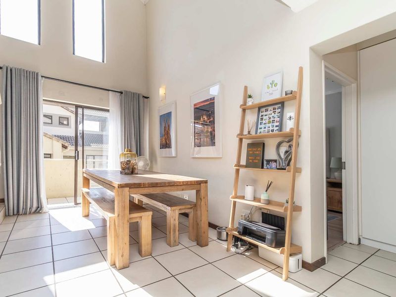 Bright double-volume living area featuring tiled flooring, large windows, and direct access to a private balcony.