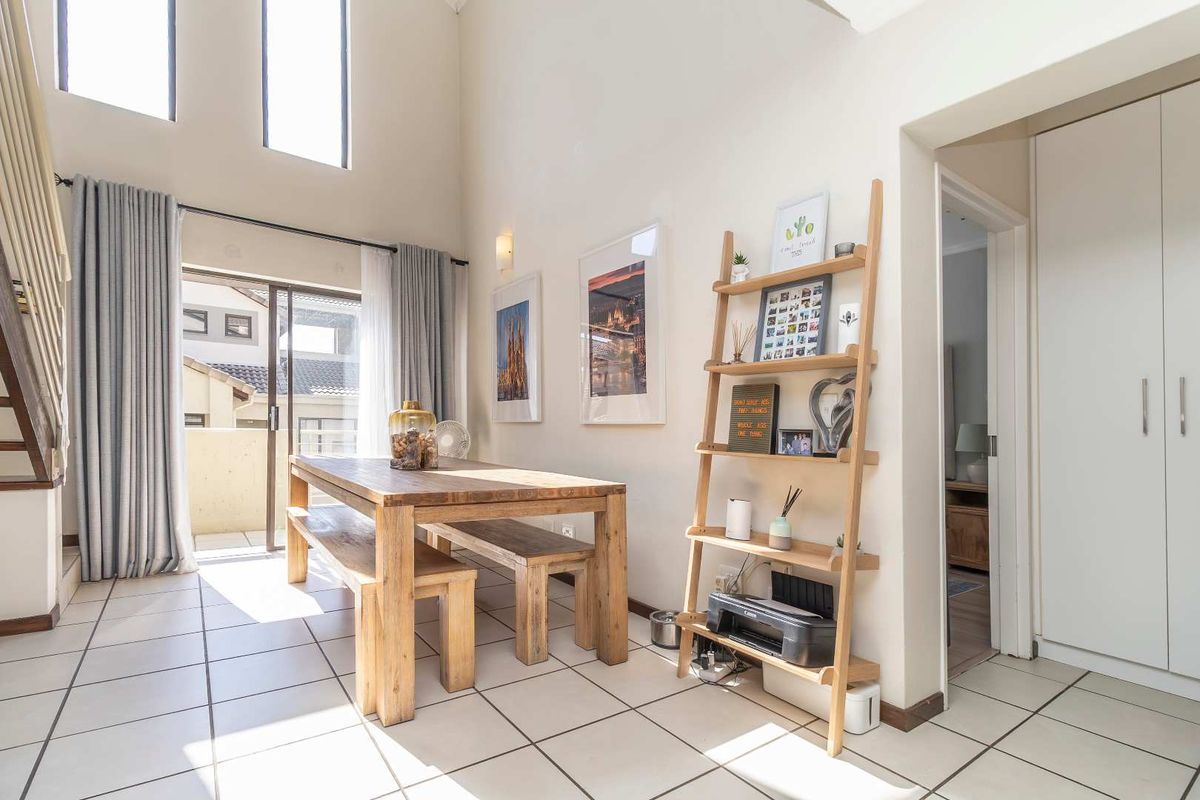 Bright double-volume living area featuring tiled flooring, large windows, and direct access to a private balcony.