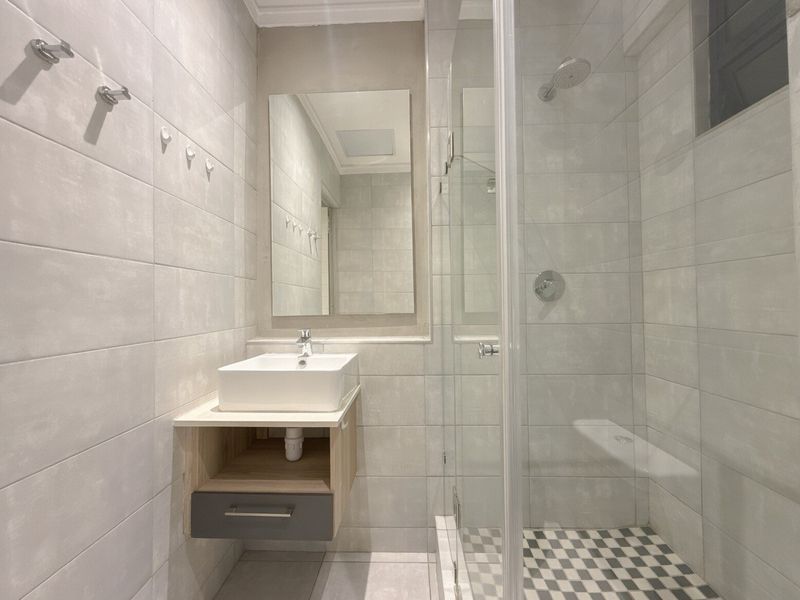 Modern bathroom featuring a wall-mounted vanity with a vessel sink, a glass-enclosed shower, and neutral tiled finishes throughout.
