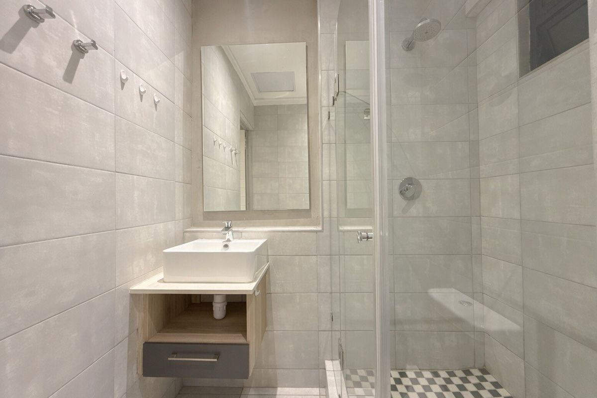 Modern bathroom featuring a wall-mounted vanity with a vessel sink, a glass-enclosed shower, and neutral tiled finishes throughout.