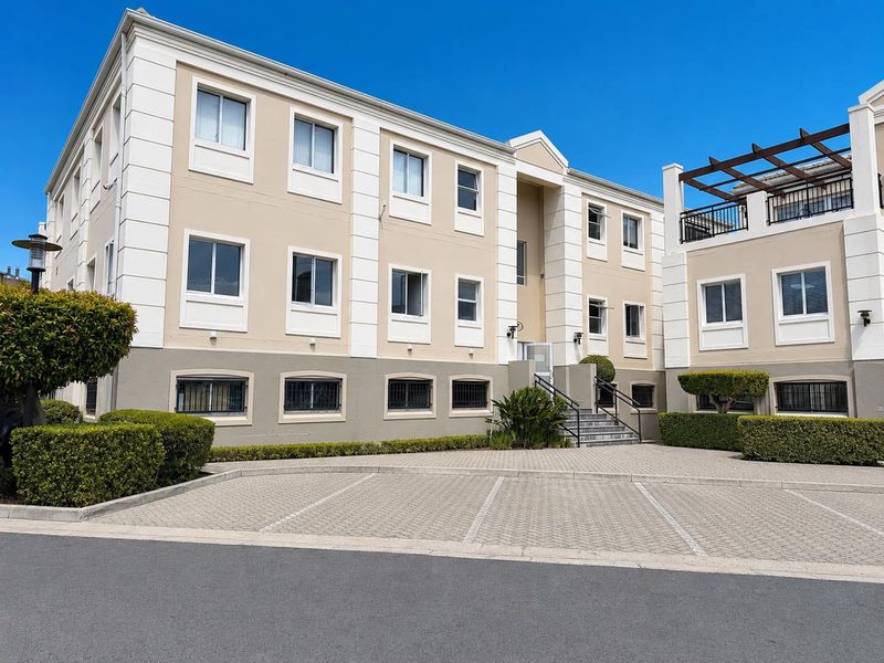 Front exterior view of a multi-story office building featuring a paved parking area, structured facade, and well-maintained landscaping.