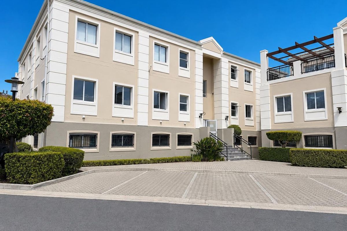 Front exterior view of a multi-story office building featuring a paved parking area, structured facade, and well-maintained landscaping.