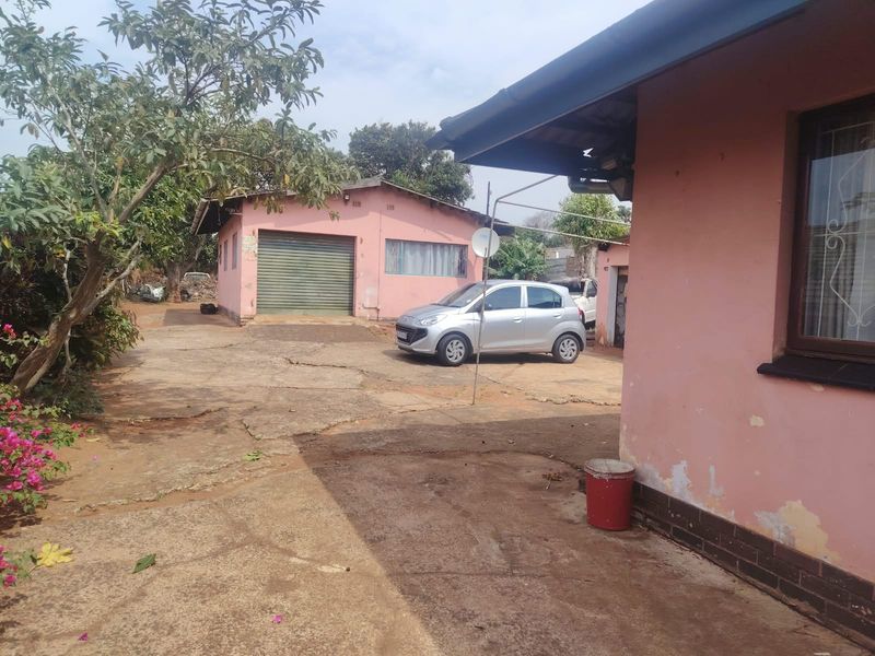 Rear exterior view showing a detached garage, concrete driveway, and the rear facade of the main house with visible paint wear.