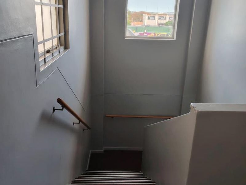 A functional interior staircase featuring carpeted steps, wooden handrails, and security bars on the window.