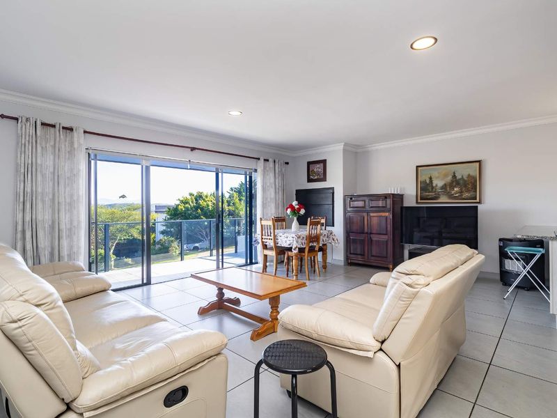 Spacious open-plan living and dining area featuring tiled floors, recessed lighting, and large sliding glass doors leading to an outdoor balcony.