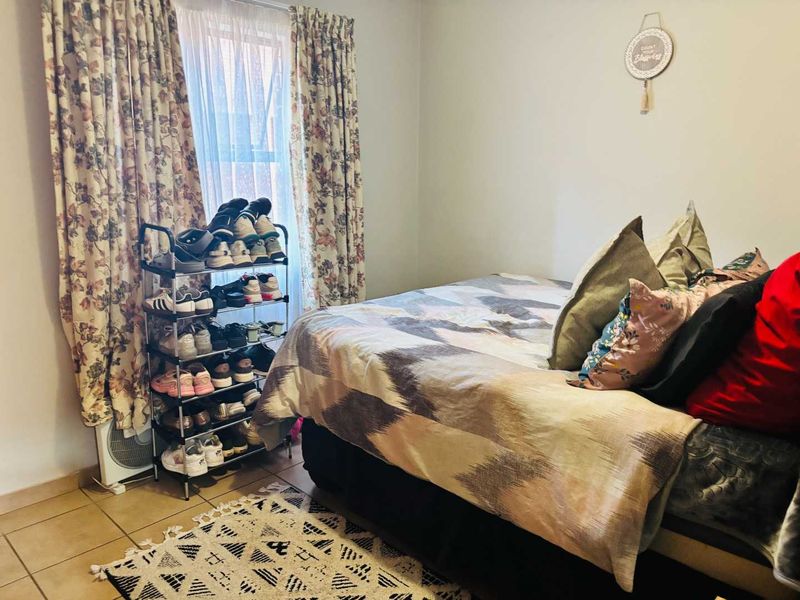 A standard bedroom featuring tiled flooring and a window with curtains, providing a functional living space.