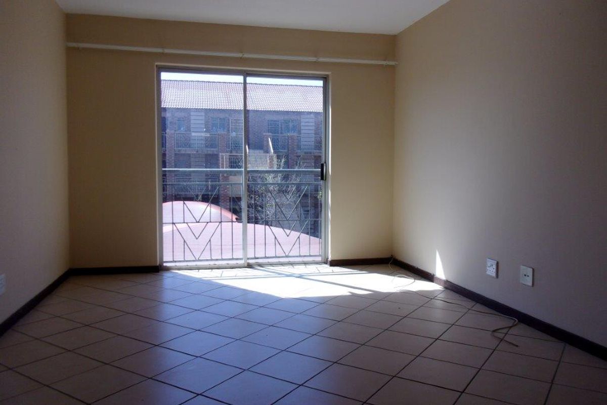 An empty living room featuring tiled flooring and a sliding glass door that opens onto a balcony.