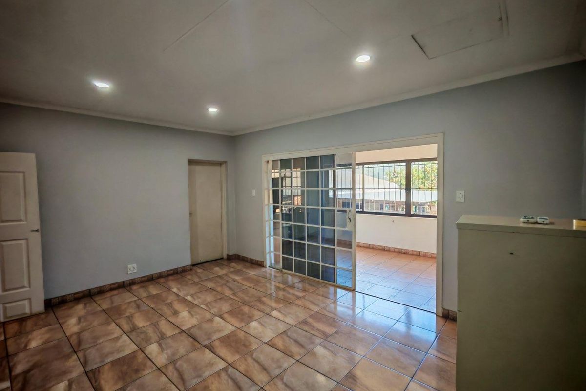 Spacious living area featuring tiled flooring, recessed ceiling lighting, and a sliding glass door providing access to an enclosed patio space.