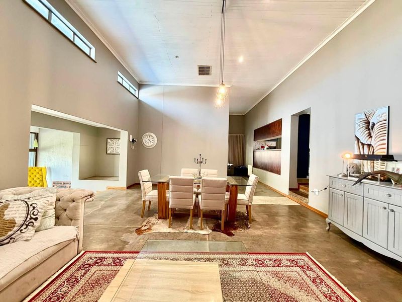 Spacious open-plan living and dining area featuring high vaulted ceilings, clerestory windows, and polished concrete flooring, offering a bright and airy atmosphere.