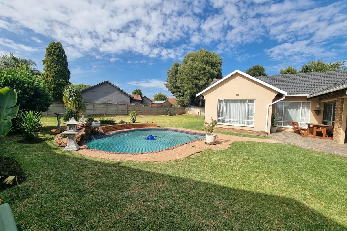 A well-maintained rear garden featuring a swimming pool with a safety net, brick paving, and a paved patio area adjacent to the house.