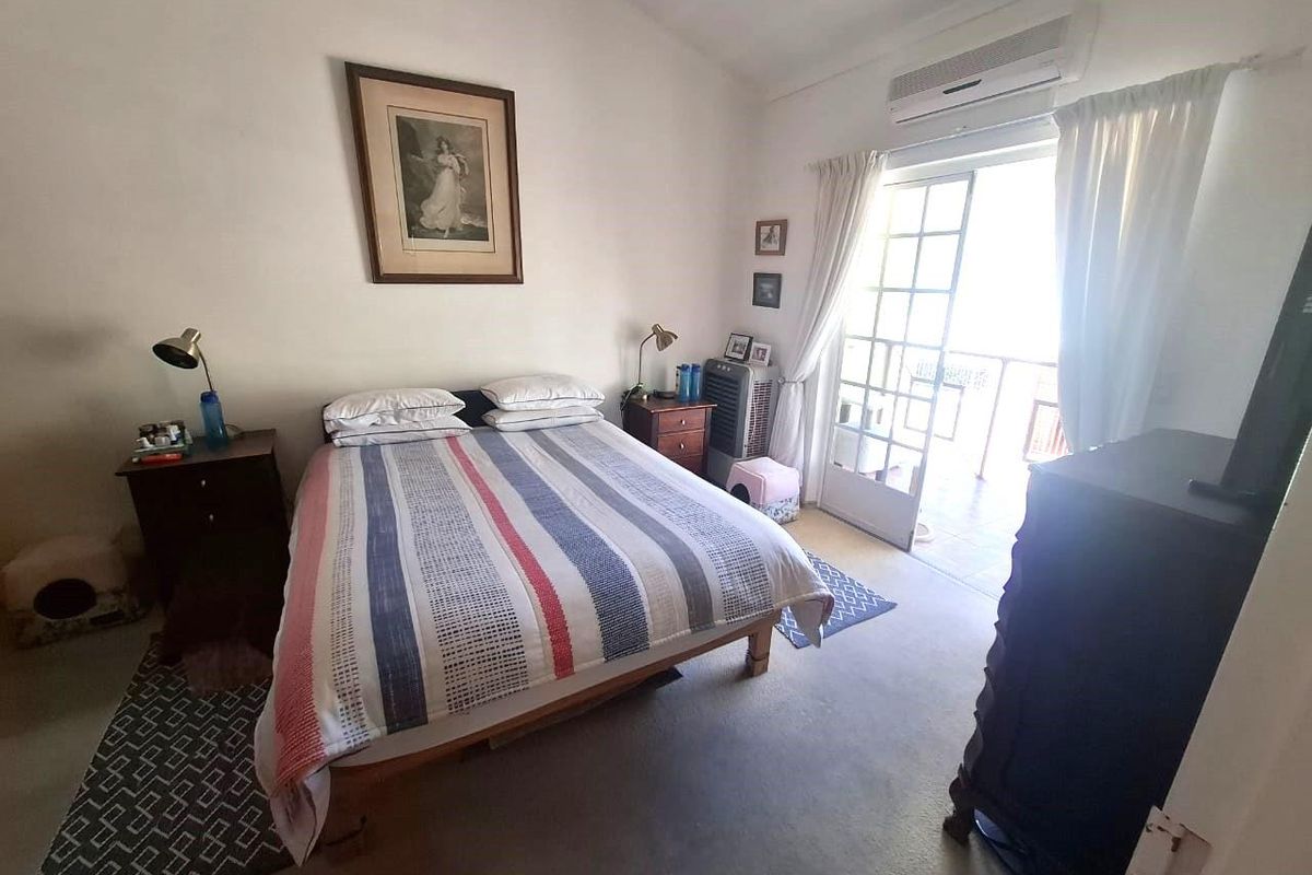 A bedroom featuring carpet flooring, a wall-mounted air conditioning unit, and French doors providing access to an outdoor balcony area.