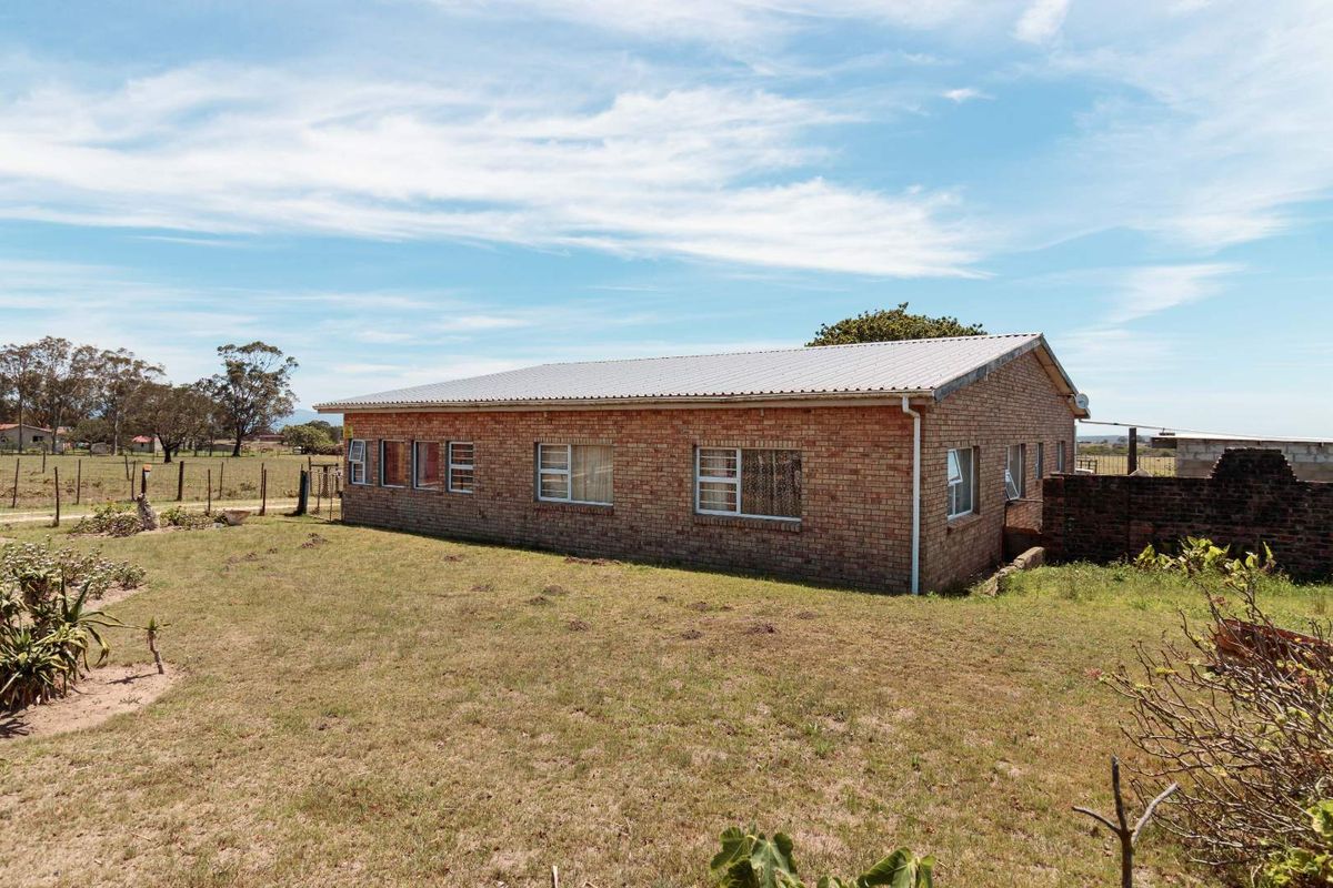 A view of the rear exterior of a brick farmhouse featuring a corrugated metal roof and surrounding rural landscape.