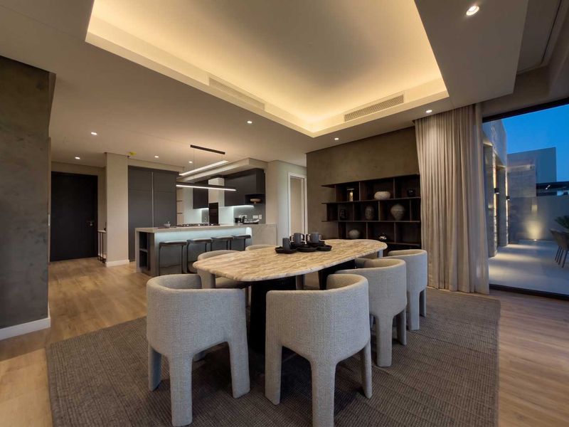 Modern open-plan living and dining area featuring recessed ceiling lighting, ducted air conditioning, and a sleek kitchen island with integrated cabinetry.