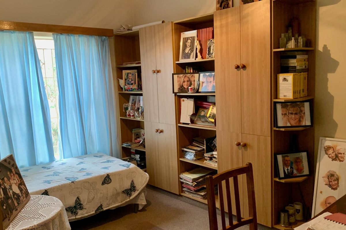 A bedroom featuring built-in wooden cabinetry and shelving units, providing ample storage space with a functional layout.