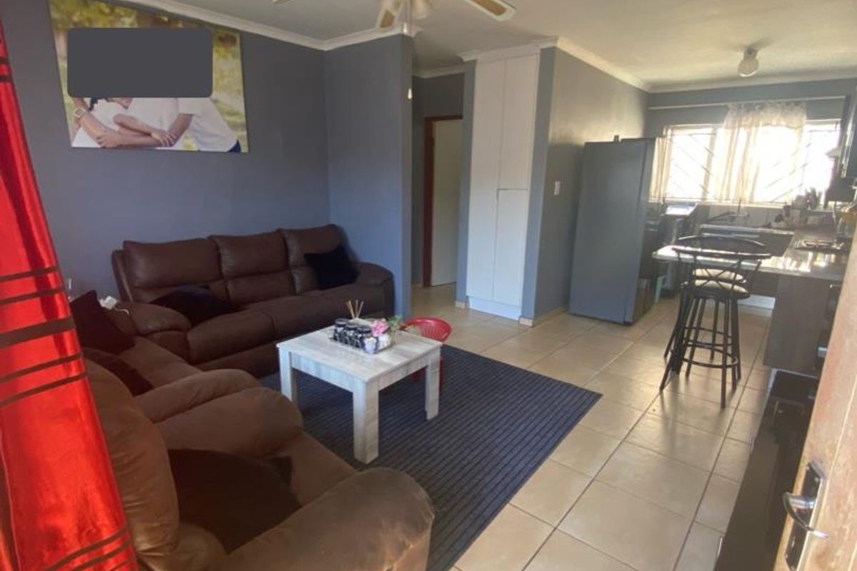 Open-plan living and kitchen area featuring tiled flooring, a ceiling fan, and built-in storage cupboards.