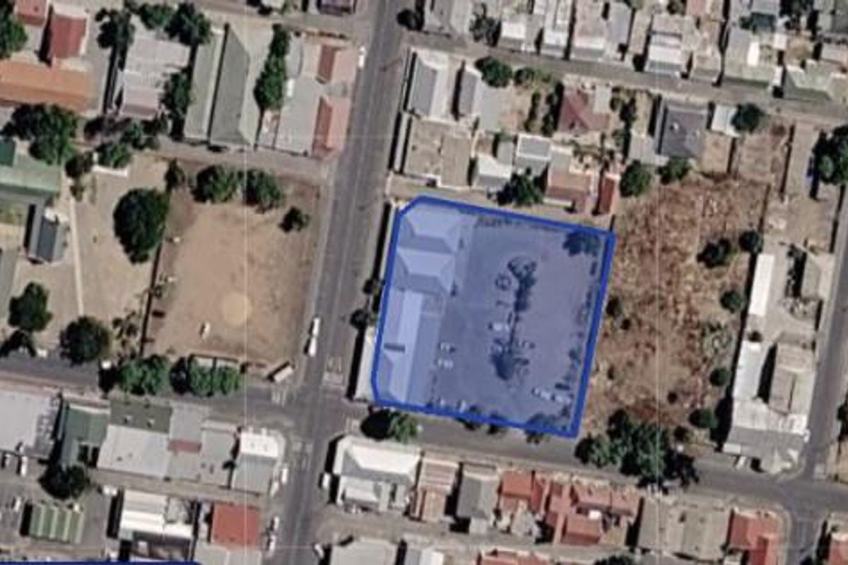 Aerial view of the industrial property highlighting the building footprint and associated asphalt parking area within the urban block.